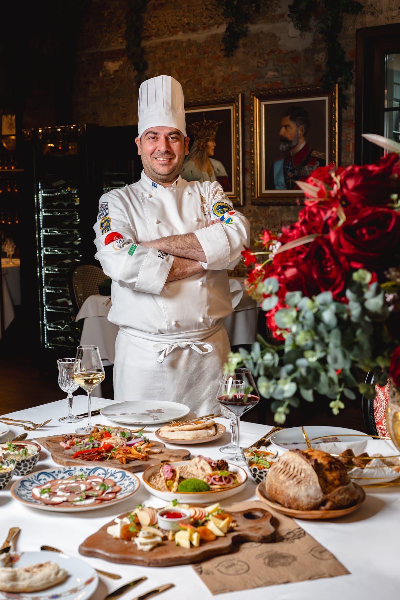 Chef Valentin Bodnar în fața mesei cu preparate semnătură, sub portretele regale Dacia Romanian Dining